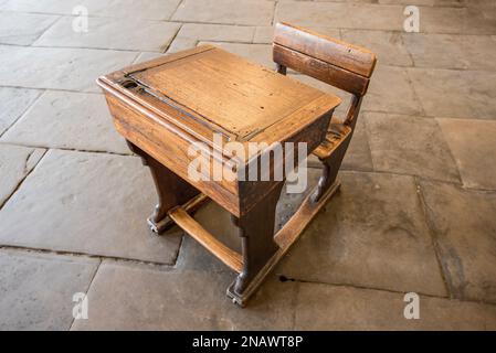 Sopravvissuto, vecchio stile vittoriano, scrivania scuola in legno con sedile rigido fisso e cerniera superiore seduto su un pavimento in pietra al Salts Mill, villaggio di Saltaire Foto Stock