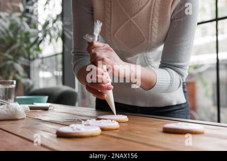 Chef femminile che decora pan di zenzero con sacchetto di pasta sfoglia Foto Stock
