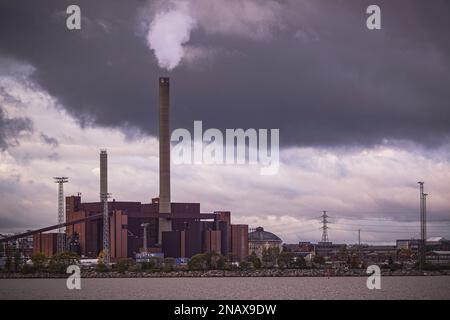 Il fumo che emette dalla fabbrica contro il cielo nuvoloso Foto Stock