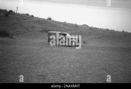 1950s, storico, all'esterno in mezzo a un campo collinare, un ragazzino seduto nella sede anteriore di un piccolo furgone di consegna dell'epoca, Inghilterra, Regno Unito. Nome sul lato del furgone, Vickery, Fruits & Flowers, di Derby & Long Eaton. Foto Stock