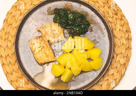 Salmone sano ricco di omega-3, spinaci ricchi di nutrienti, patate salate classiche su un tavolo Foto Stock