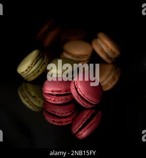 Concediti un momento di decadenza con questi squisiti macaron sullo sfondo nero Foto Stock