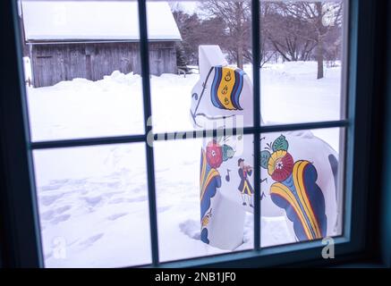 Vista dalla finestra del Museo Gammelgarden di un cavallo di dala e di un fienile d'epoca in una giornata invernale a Scandia, Minnesota USA. Foto Stock