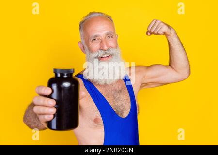 Foto della persona anziana sportiva mostra spazio vuoto braccio bottiglia flexing bicipite isolato su sfondo giallo Foto Stock