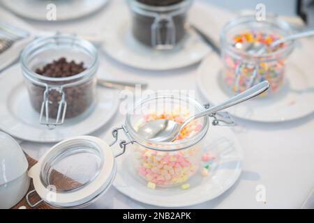 Un'inquadratura ad angolo alto dei colorati e dolci spruzzi e cioccolatini in vasetti di vetro Foto Stock