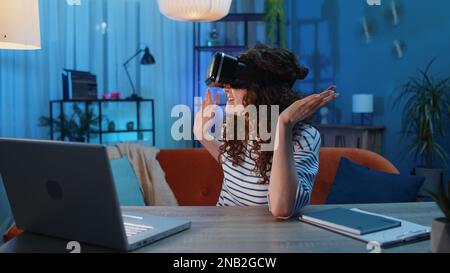 Donna che utilizza la realtà virtuale tecnologia futuristica VR app visore casco giocare simulazione 3D 360 videogioco guardare film film in casa appartamento. Ragazza in occhiali seduti sul divano. Effetto zoom transizione Foto Stock