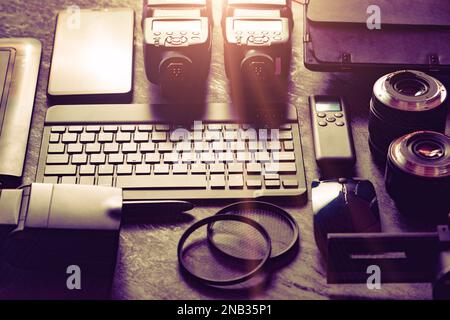 Workstation fotografica digitale su sfondo nero. Vista dall'alto di fotocamera digitale, flash, obiettivo e computer portatile. Attrezzature fotografiche professionali. Foto Stock