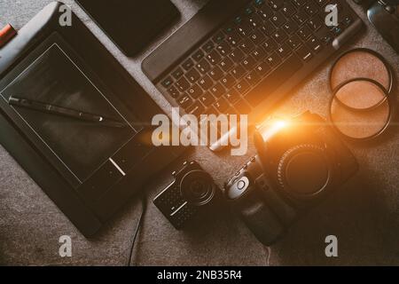 Workstation fotografica digitale su sfondo nero. Vista dall'alto di fotocamera digitale, flash, obiettivo e computer portatile. Attrezzature fotografiche professionali. Foto Stock