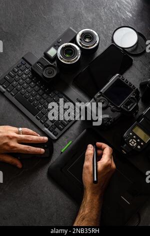 Workstation fotografica digitale su sfondo nero. Vista dall'alto di fotocamera digitale, flash, obiettivo e computer portatile. Attrezzature fotografiche professionali. Foto Stock