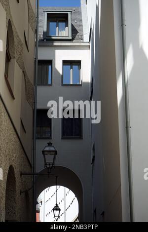 Una bella vista di un'entrata ad arco in pietra su un edificio bianco visto su una strada stretta Foto Stock