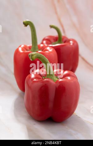Un primo piano di tre peperoni rossi interi Foto Stock