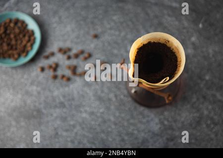 Preparazione del caffè versato in un contenitore di vetro sul piano di appoggio in pietra pulita con fondo in marmo bianco Foto Stock