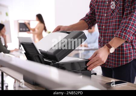 Dipendente che utilizza una stampante moderna in ufficio, in primo piano Foto Stock