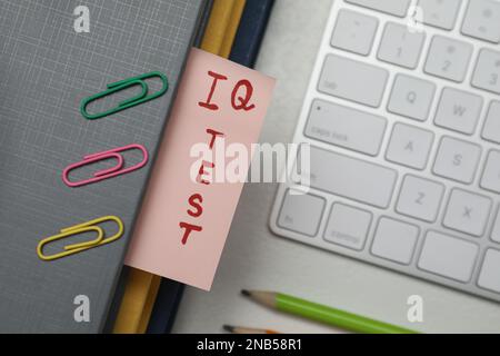 Carta con parole IQ Test in notebook, tastiera e dispositivi di fissaggio su tavolo da ufficio, piatto Foto Stock
