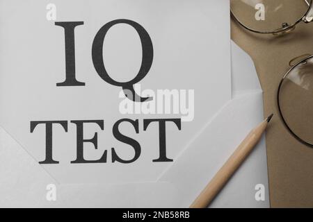 Carta con parole IQ Test in busta e matita su notebook, a posa piatta Foto Stock
