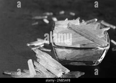 Cristalli di mentolo in ciotola su fondo grigio, primo piano Foto Stock