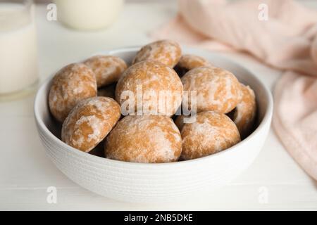 Gustosi biscotti di pan di zenzero fatti in casa in una ciotola su un tavolo bianco, primo piano Foto Stock