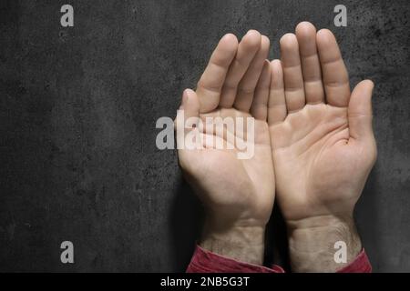 Uomo che mostra palmi pallidi al tavolo grigio, vista dall'alto con spazio per il testo. Sintomo di anemia Foto Stock