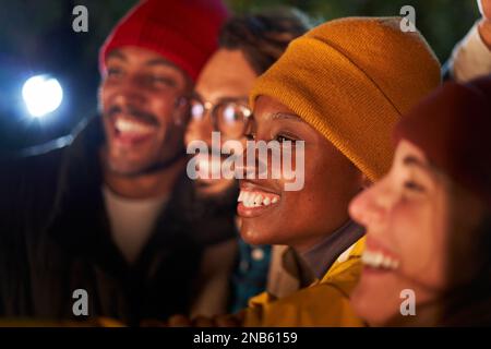 I ragazzi e le ragazze multirazziali sorridono e prendono selfie in inverno all'aperto di notte. Foto Stock