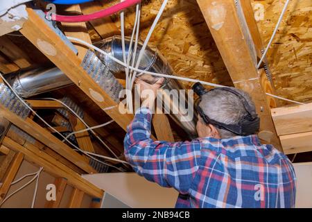 Durante la ricostruzione, installare a casa i nuovi condotti montati sui tubi di sfiato HVAC nel soffitto Foto Stock