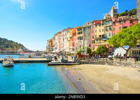 Una piccola spiaggia di sabbia nel colorato villaggio costiero di Porto Venere, in Italia, sulla costa ligure, con i suoi caffè, negozi e porticciolo. Foto Stock