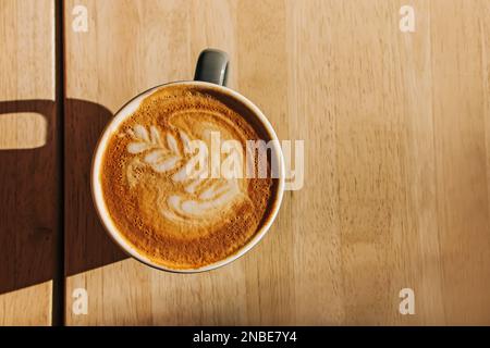 Tazza di cappuccino sul tavolo di legno nella luce naturale del mattino, vista dall'alto Foto Stock