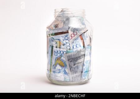 Kazakhstan banconote di grosso taglio in una banca trasparente su sfondo bianco Foto Stock
