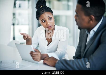 Ho bisogno di un secondo parere. due giovani uomini d'affari seduti in ufficio e in conversazione mentre si utilizza un tablet digitale. Foto Stock