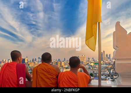 Tre monaci buddisti che guardano lo skyline di Bangkok, Thailandia, al tramonto Foto Stock