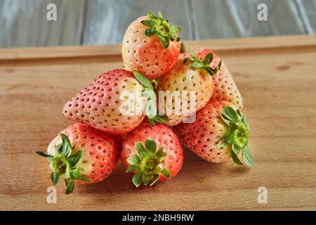 Fragole fresche selezionate, varietà di ananas impilate su fondo in legno Foto Stock