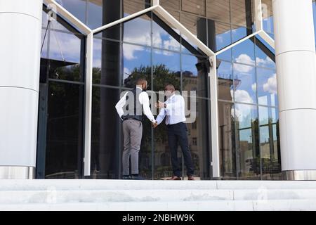 Ritratto di due uomini d'affari dalla pelle scura che camminano e parlano davanti ad un edificio moderno esterno. Meeting all'aperto Foto Stock