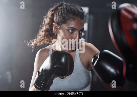 La vita può essere pericolosa, imparare come difendersi. una giovane donna che pratica con il suo allenatore in una palestra di pugilato. Foto Stock