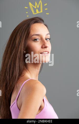 sguardo sopra la sua spalla in un ritratto di una giovane donna sottile in una canotta rosa e capelli lunghi con un'espressione di celit e vanità aumentata da a. Foto Stock