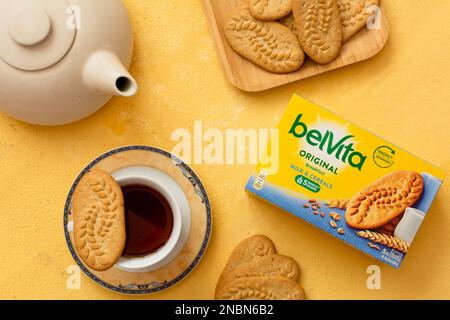 Tiraspol, Moldova - 31 gennaio 2023: Belvita colazione cereali scatola biscotti con latte smak, biscotti su piatto e tè su sfondo arancione. Selettivo Foto Stock