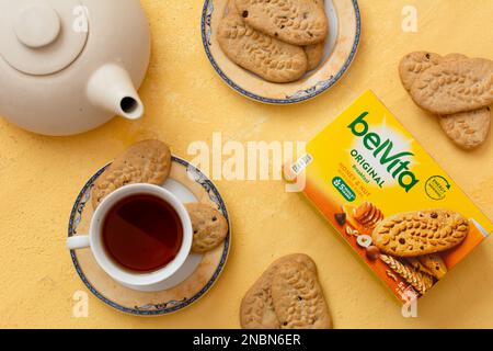 Tiraspol, Moldavia - 31 gennaio 2023: Scatola di biscotti Belvita con miele e noci smak con patatine choc, biscotti sul piatto e tè sul dorso d'arancia Foto Stock