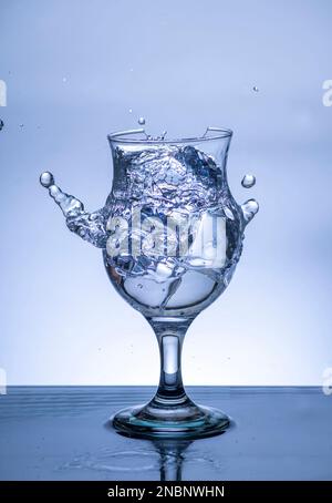 L'immagine di versare acqua potabile, in un vetro rotto, che fa sentire rinfrescato su sfondo bianco sfocato, spruzzi d'acqua, acqua frizzante, Foto Stock