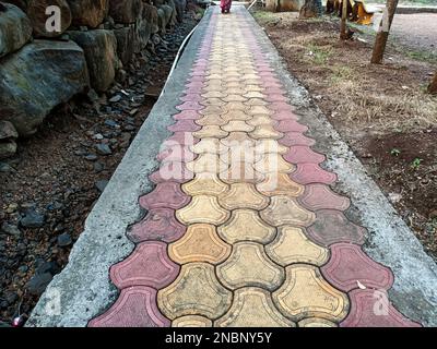 Un'asfaltatrice in cemento di colore rosso e giallo blocca il percorso nel giardino pubblico Foto Stock