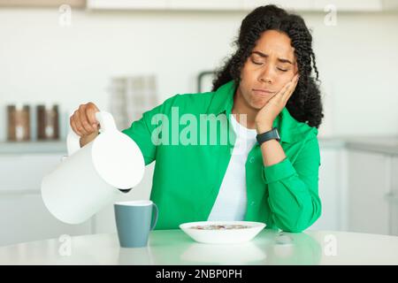 Sleepy Black Female fare caffè colazione in cucina Foto Stock