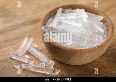 Cristalli di mentolo in ciotola su fondo di legno Foto Stock