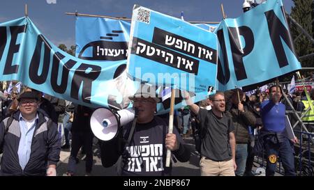GERUSALEMME, ISRAELE - 13 FEBBRAIO: I manifestanti cantano slogan e tengono una bandiera che recita "Nessuna libertà, nessuna alta tecnologia" durante una manifestazione di massa contro il nuovo piano di sistema giudiziario del governo israeliano che mira a indebolire la Corte Suprema del paese al di fuori del parlamento di Israele (Knesset) il 13 febbraio 2023, a Gerusalemme, Israele. Credit: Eddie Gerald/Alamy Live News Foto Stock