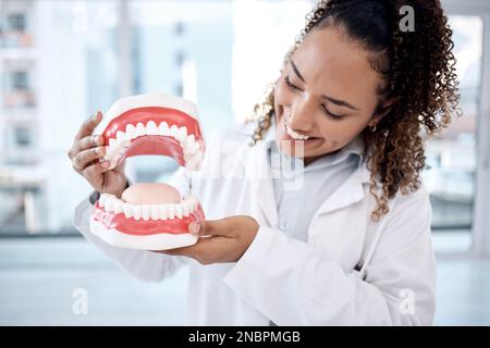 Dentista, igiene orale e dentale professionale bocca artificiale o modello nel suo ufficio per una dimostrazione di sbiancamento. Protesi dentarie, mascelle e assistenza sanitaria Foto Stock