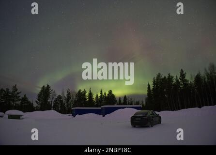 Kittila, Finlandia - 12 febbraio 2023: Paesaggi meravigliosi in Lapponia, Finlandia. Una Tesla modello 3 di colore nero pieno sotto la bella aurora boreale Foto Stock