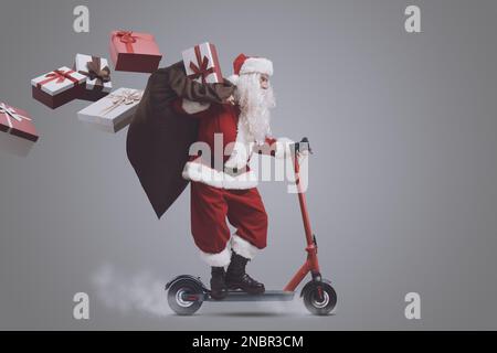 Fast Babbo Natale consegna regali la vigilia di Natale, è a bordo di uno scooter elettrico ecologico Foto Stock