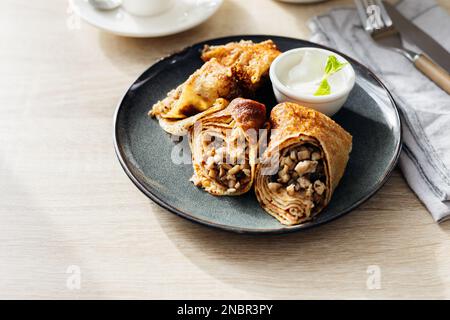 Pancake russo con pollo e funghi con panna acida Foto Stock