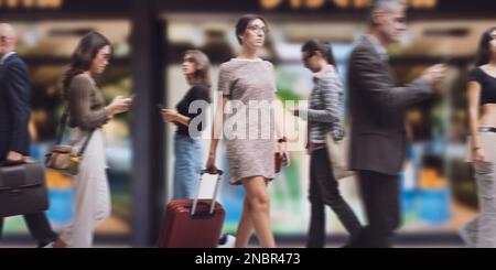Giovane donna viaggiatore nella strada della città e folla di persone a piedi Foto Stock