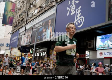 Hong Kong, Cina. 12th Feb, 2023. Un corridore visto determinato a finire la sua corsa mentre corre accanto alla pubblicità della maratona. La maratona di Hong Kong Standard Chartered ritorna mentre oltre 30.000 corridori hanno sfidato il clima umido per competere in una giornata di nebbia. Il concorso annuale è stato sospeso per circa un anno a seguito della covida restrizione della città. Nonostante la città lentamente rilassando le sue misure di distanziamento sociale, i corridori devono indossare maschere prima e dopo la gara. (Foto di Ashley Chan/SOPA Images/Sipa USA) Credit: Sipa USA/Alamy Live News Foto Stock