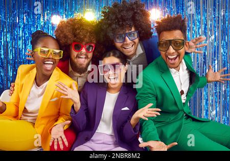 Ritratto di gruppo divertente di giovani felici vestiti in costumi luminosi. Foto Stock