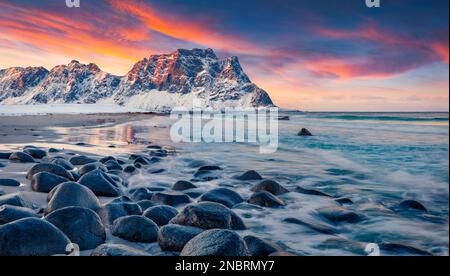 La prima luce del sole che risplana enorme picco su Haukland Beach, Vastvagoy. Tramonto mozzafiato con orizzonte infinito sull'isola di Lofoten, Norvegia, Europa. Incredibile Seascap Foto Stock