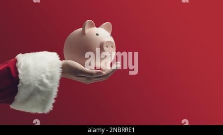 Babbo Natale che tiene una banca del piggy sul fondo rosso, soldi di risparmio e concetto di investimenti Foto Stock