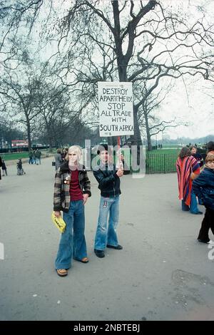 Londra 1977. Un giovane che tiene un segno manoscritto con il testo Destroy Apartheid! Fermare tutti gli scambi commerciali con il Sud Africa. I due uomini indossano i tipici jeans a zampa larga che erano un 1970s moda. Kristoffersson Ref DV2 Foto Stock